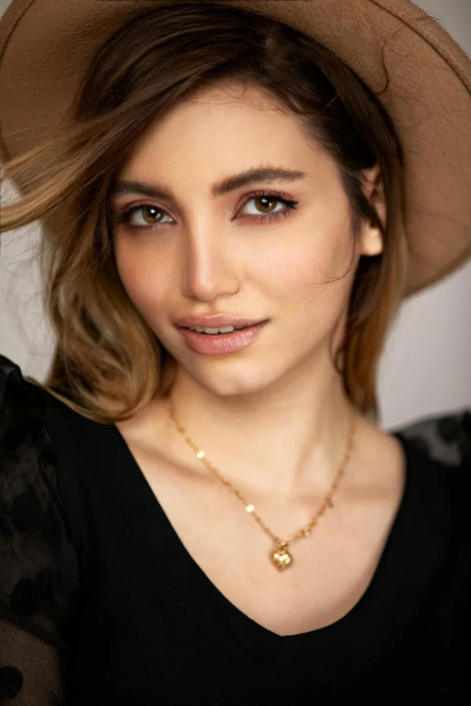 Une femme portant un chapeau marron et un haut noir souriant