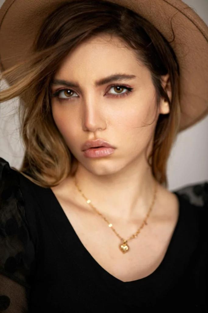 Eraseid a créé l'image d'une femme portant un chapeau marron et un haut noir avec un collier en or