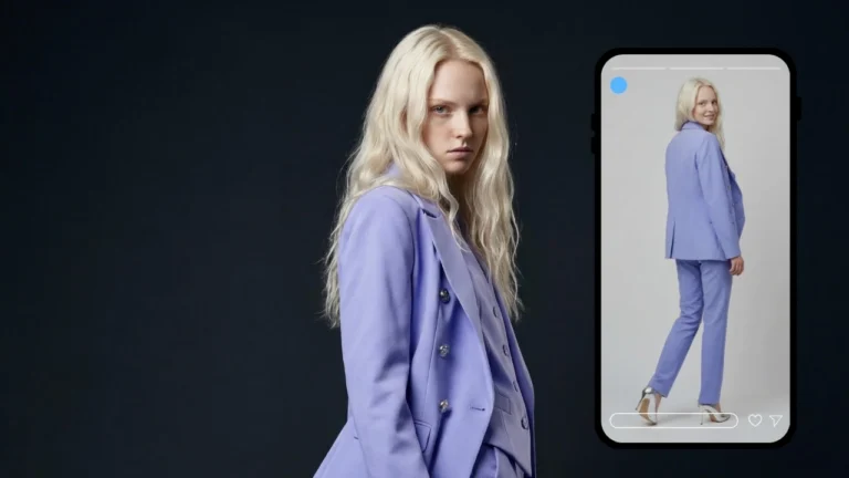Un anuncio de moda protagonizado por una mujer rubia de cabello largo y ondulado, que viste un blazer cruzado color lavanda y pantalones a juego. Se sitúa a la izquierda del encuadre, sobre un fondo oscuro, mirando directamente a la cámara con expresión seria. A su derecha, la pantalla de un smartphone muestra una imagen de la misma mujer desde otro ángulo —una vista trasera de cuerpo entero— como si se tratara de una aplicación o tienda online. La pantalla incluye elementos de interfaz de usuario, como un punto azul de grabación en la parte superior e iconos en la inferior, que sugieren una experiencia de compra interactiva o de realidad aumentada. La estética general es moderna, minimalista y de alta costura.
